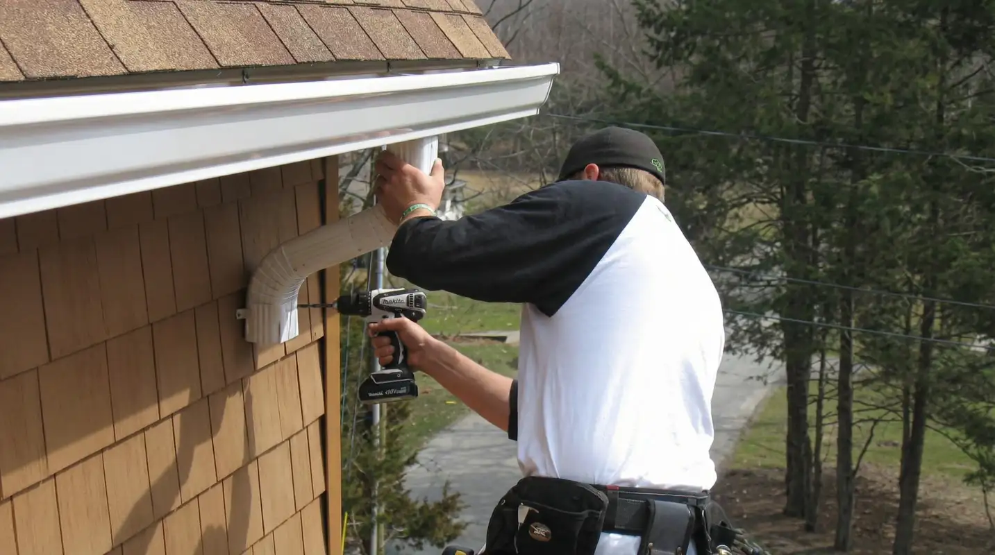 Professional contractor installing tan vinyl siding panels on a residential home exterior in Fargo, ND